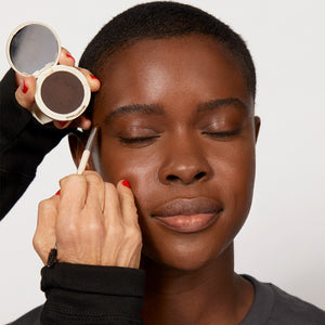A professional makeup artist using Jones Road Beauty's The Eyebrow Brush on a woman's brows