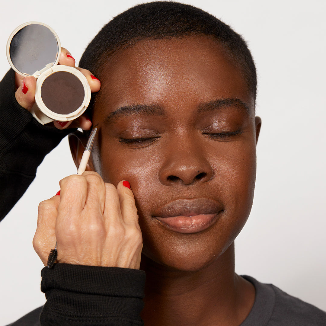 A professional makeup artist using Jones Road Beauty's The Eyebrow Brush on a woman's brows